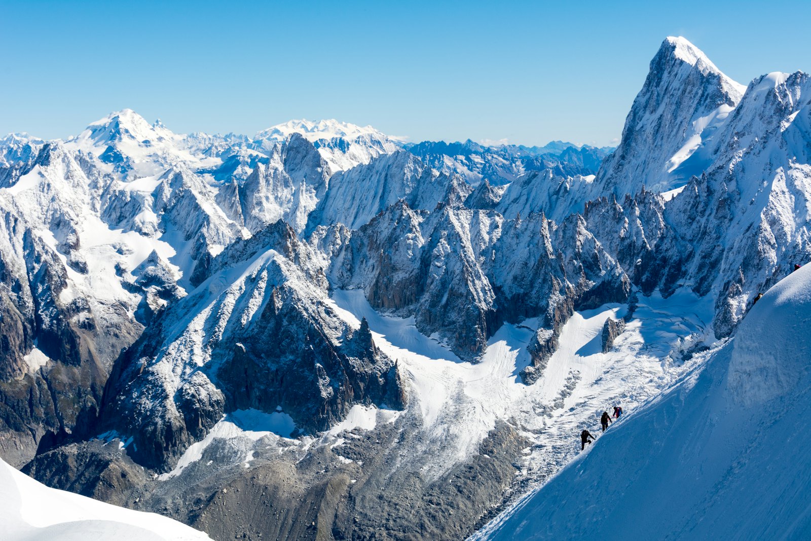Alpinists on a snow ridge below the Mont-Blanc massif above Chamonix